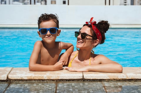 Happy Mom and son in sunglasses in the pool