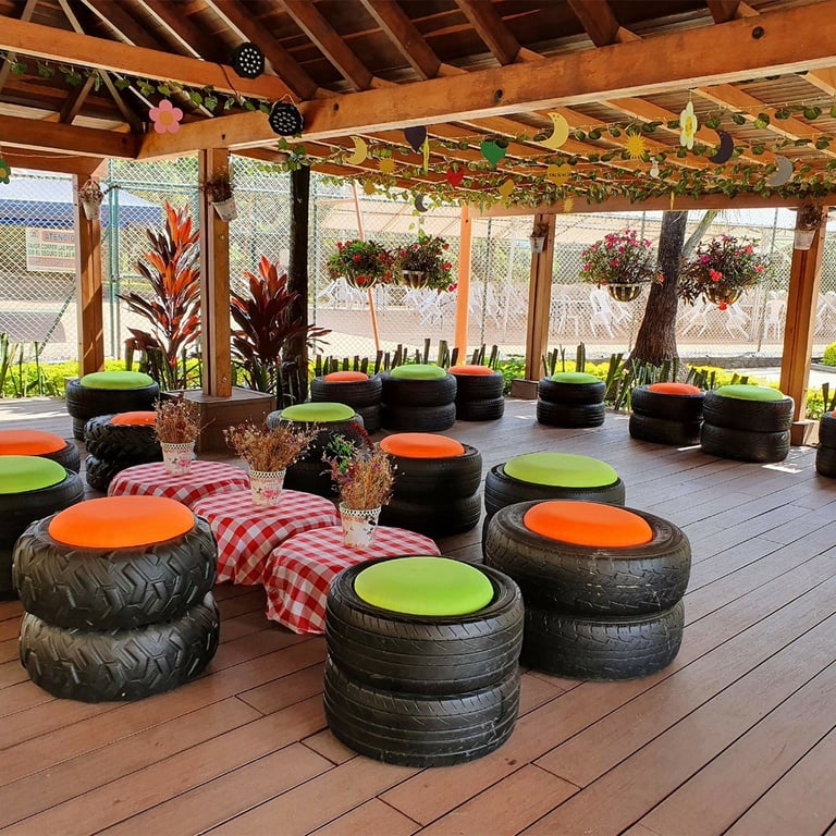 Covered outdoor seating area with recycled tire ottomans topped with orange and green cushions and red checkered fabric